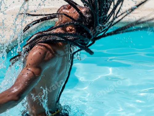 Preview: Black man with afro hair and dreadlocks comes out of the pool splashing water.
