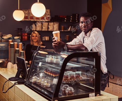 Preview: Two young multiracial baristas dressed in aprons working at their trendy coffee shop.