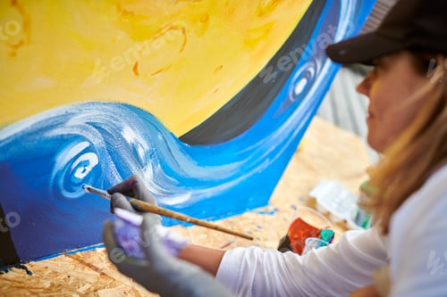 Visualização: Pintora feminina desenha quadro com pincel sobre tela para exposição de rua ao ar livre