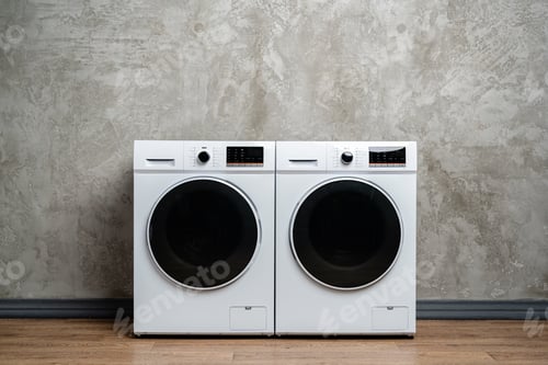Preview: Two White Washing Machines Against a Concrete Wall