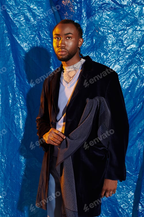 Preview: Handsome young man posing confidently against a vibrant blue backdrop with stylish attire