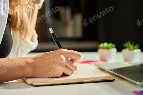 Preview: Illustrator drawing sketches in notebook at home office desk