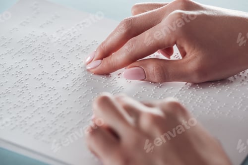 Preview: cropped view of young woman reading braille text on white paper
