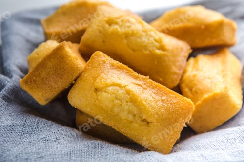 Preview: Close-up of corn muffins on plate with bowl of corn meal and additional muffins in the background.