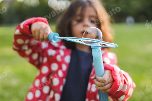 Preview: Portrait of a beautiful caucasian holds a soap bubble on a bottle with a stick in a park