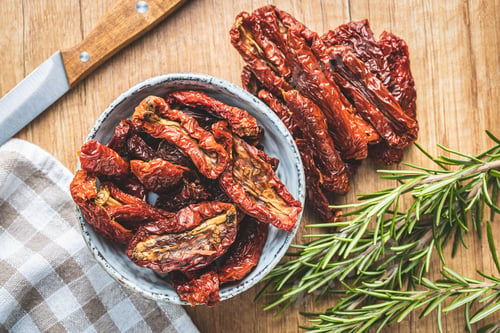 Preview: Sun dried tomatoes in bowl on wooden table.