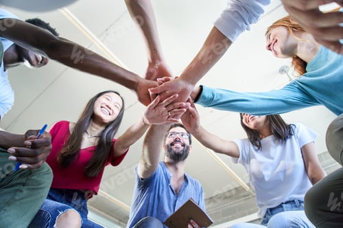 Preview: Low angle view of a group of happy young students with teacher stacking hands hands .