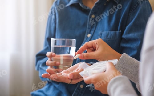 Preview: Closeup image of a woman holding and giving pills to her friend