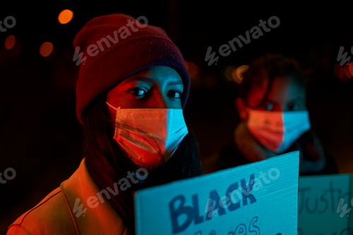 Preview: Close-up of an African-American girl holding a banner while standing in a crowd of protesters