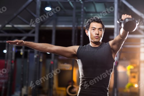 Preview: Young man training with kettlebell in crossfit gym