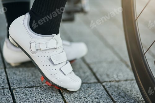 Preview: Close up shot of legs of female cyclist wearing cycling shoes standing with her bike