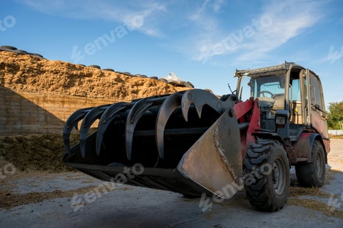 Preview: Farmer unloading round bales of straw with a front end loader