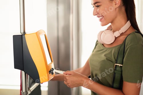 Preview: Cheerful woman passenger using vending tickets machine in the tram
