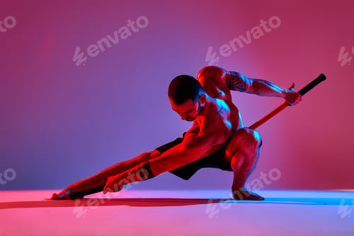 Preview: athlete men silhouette with stick training karate using sports tool in studio on colorfull lights