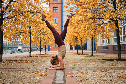 Preview: Side view of attractive girl in sportswear doing yoga exercises on city street