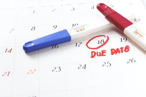 Preview: Pregnancy test with positive result lying on calendar background. soft focus.