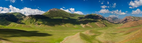 Preview: Green mountains in the afternoon under a cloudy sky.