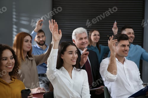 Preview: People raising hands to ask questions at seminar in office