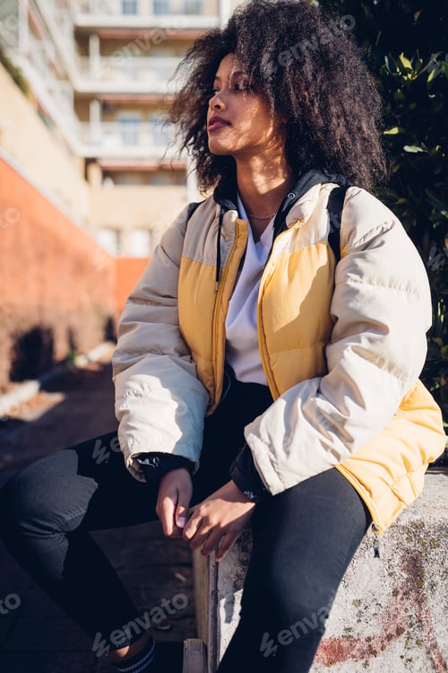 Preview: Cool young woman sitting on urban wall