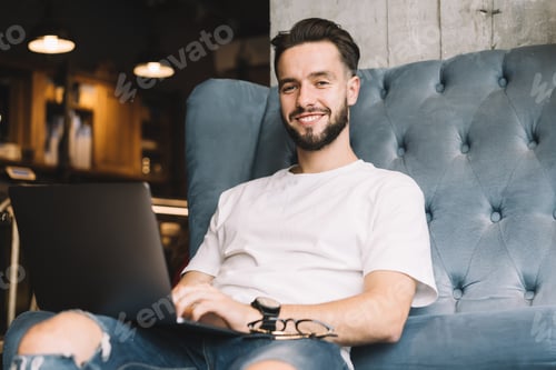 Preview: Cheerful male blogger with modern netbook technology enjoying leisure time for networking