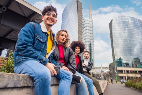 Preview: Group of four people friends tourist multiethnic sitting outdoor looking camera smiling