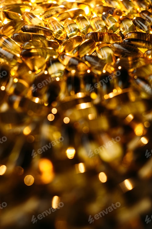 Preview: Many yellow Vitamin D, Fish Oil, Omega-3 capsules in sunshine light on table. Soft Fish Oil