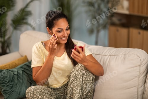 Preview: Woman Applying Makeup While Sitting on Couch Indoors