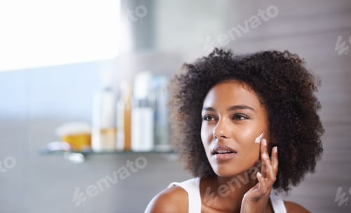 Preview: Keeping my face silky smooth. An attractive young woman applying cream to her face.