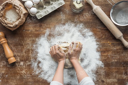 Preview: top view of female hands making dough on wooden table