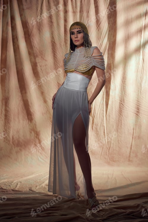 Preview: Full length of elegant brunette woman in egyptian attire posing on abstract background