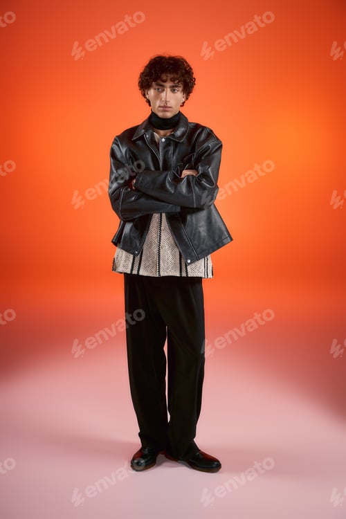 Preview: Handsome stylish man poses confidently against a vibrant orange background in a modern setting