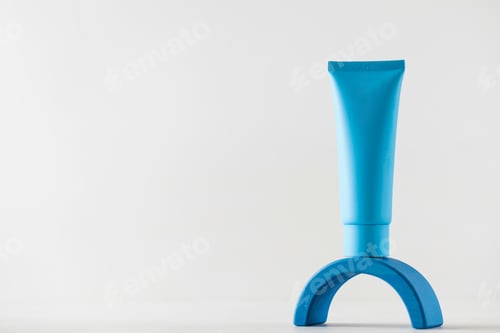 Preview: Blue tube with cosmetic product, cream on a pedestal on a light background.