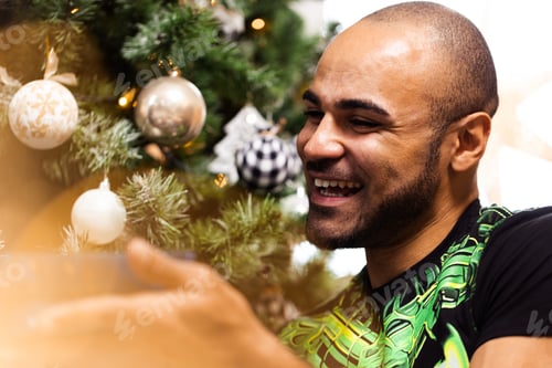 Preview: African American man decorating Christmas tree at home