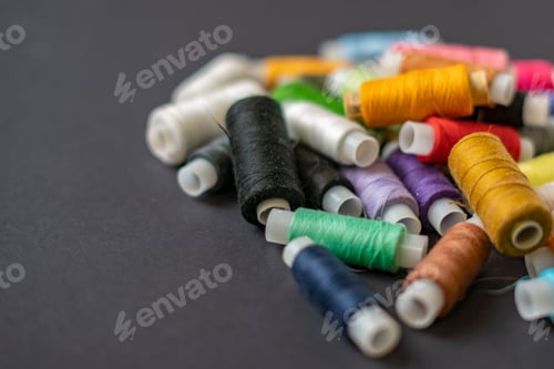 Preview: bunch of colorful sew threads lay on dark background isolated d