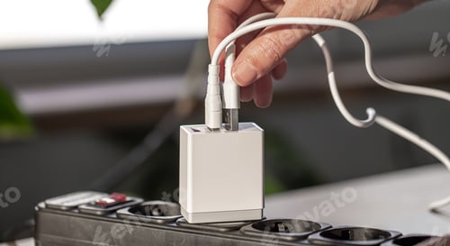 Preview: White USB charging for gadgets on a blurred background of the room, close-up.