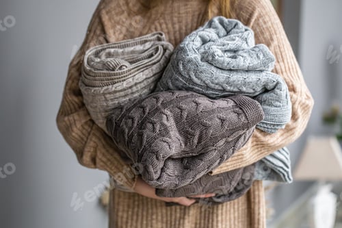 Preview: Warm knitted blankets in pastel colors in women's hands.