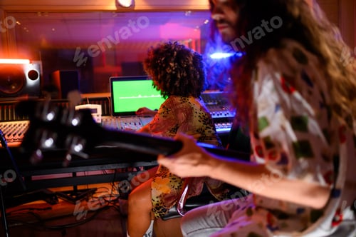 Preview: Female music producer examining the recording process on display monitor in music studio.