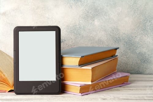 Preview: Digital tablet with a stack of books on gray background
