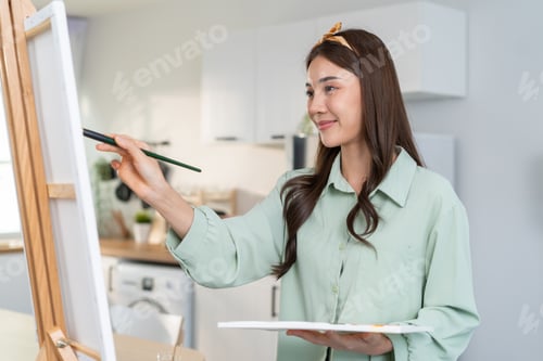 Preview: Asian young talented woman artist coloring on painting board in house.