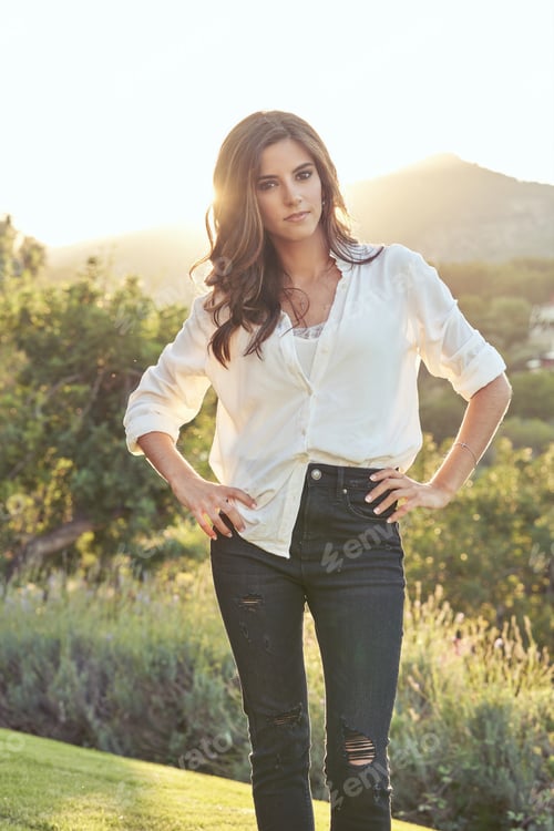 Preview: Self confident woman standing in field at sundown