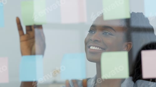 Preview: Female Entrepreneur Putting Notes On Glass Board In Modern Office