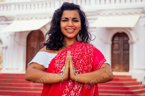 Preview: Young Indian woman in traditional sari red dress praying in a hindu temple goa