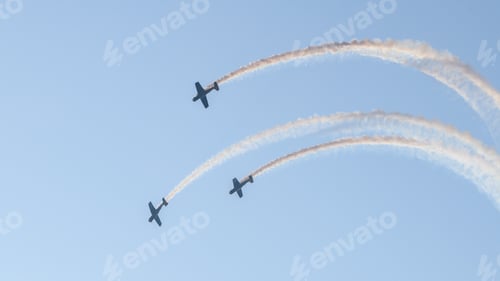 Preview: Three aerobatic aircraft performing a synchronized aerial maneuver with curved smoke trails