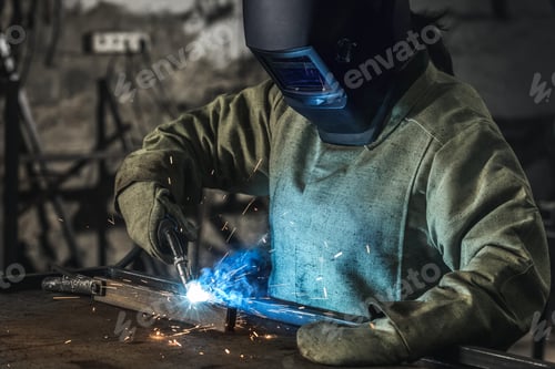 Preview: manual worker in protective helmet with welding torch working in workshop