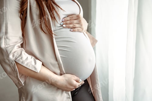Preview: Close up of belly of a pregnant woman standing by the window.