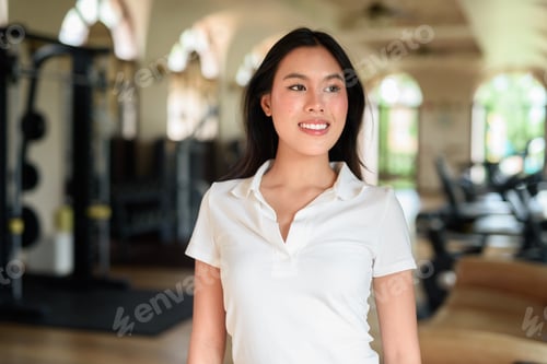 Preview: Young Asian woman in polo shirt at gym, casual fitness lifestyle, modern indoor training location