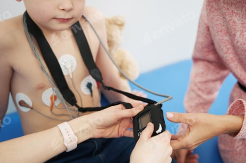 Preview: Doctor examining little boy with ECG holter monitor in clinic