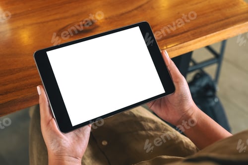 Preview: a woman sitting and holding black tablet pc with blank white desktop screen horizontally
