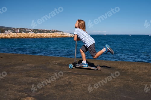 Preview: Boy riding a scooter on a pier at sunny day