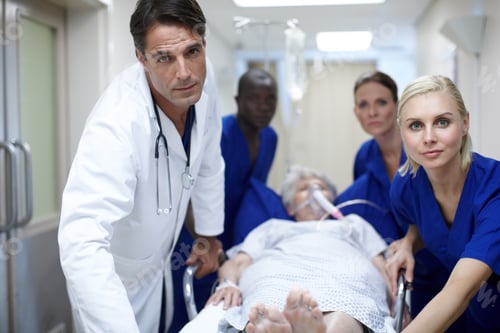 Preview: Taking her to the OR. Portrait of a group of doctors pushing a patient down the hall.